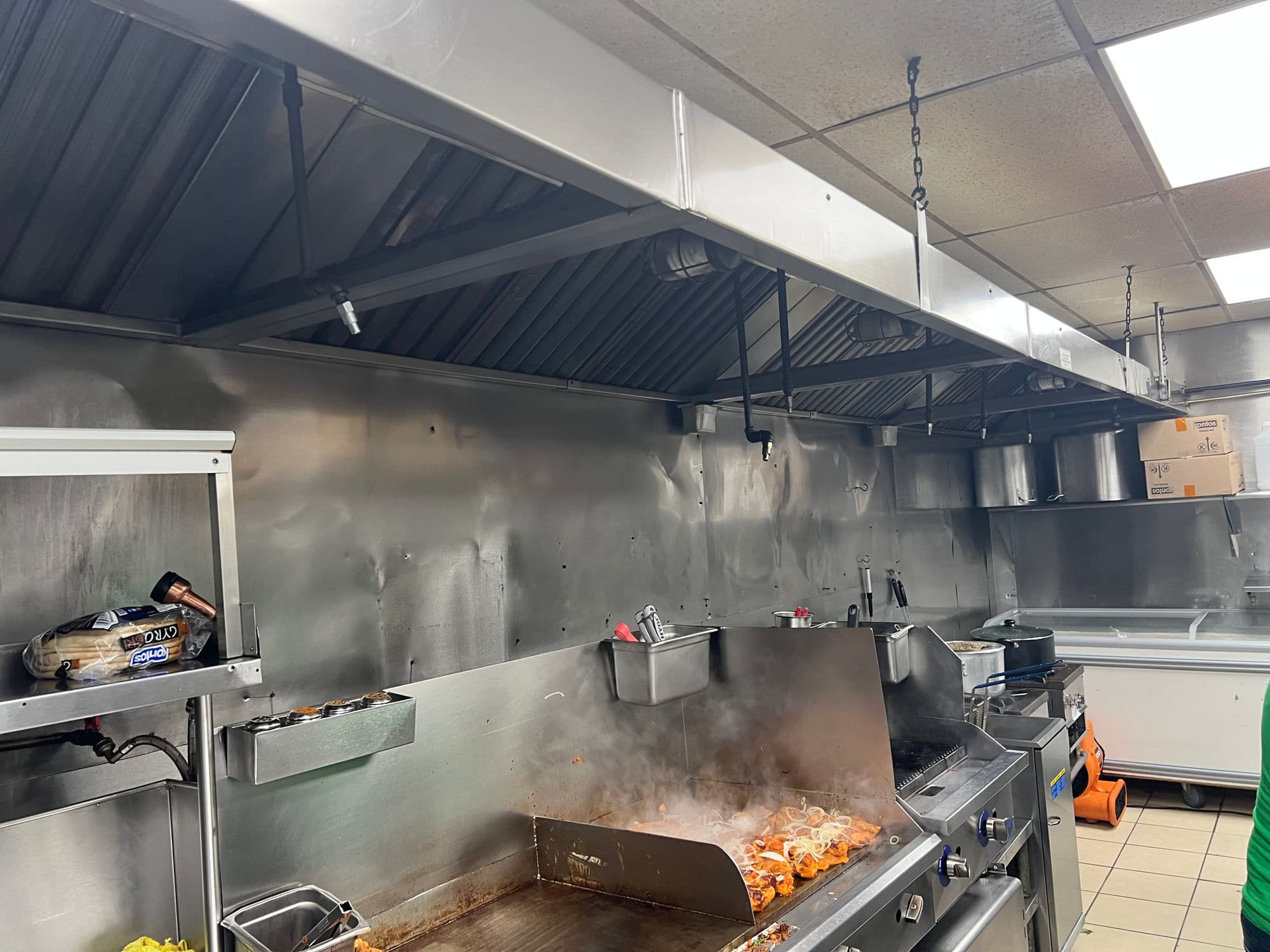 Stainless steel commercial range hood installed over a cooking line
